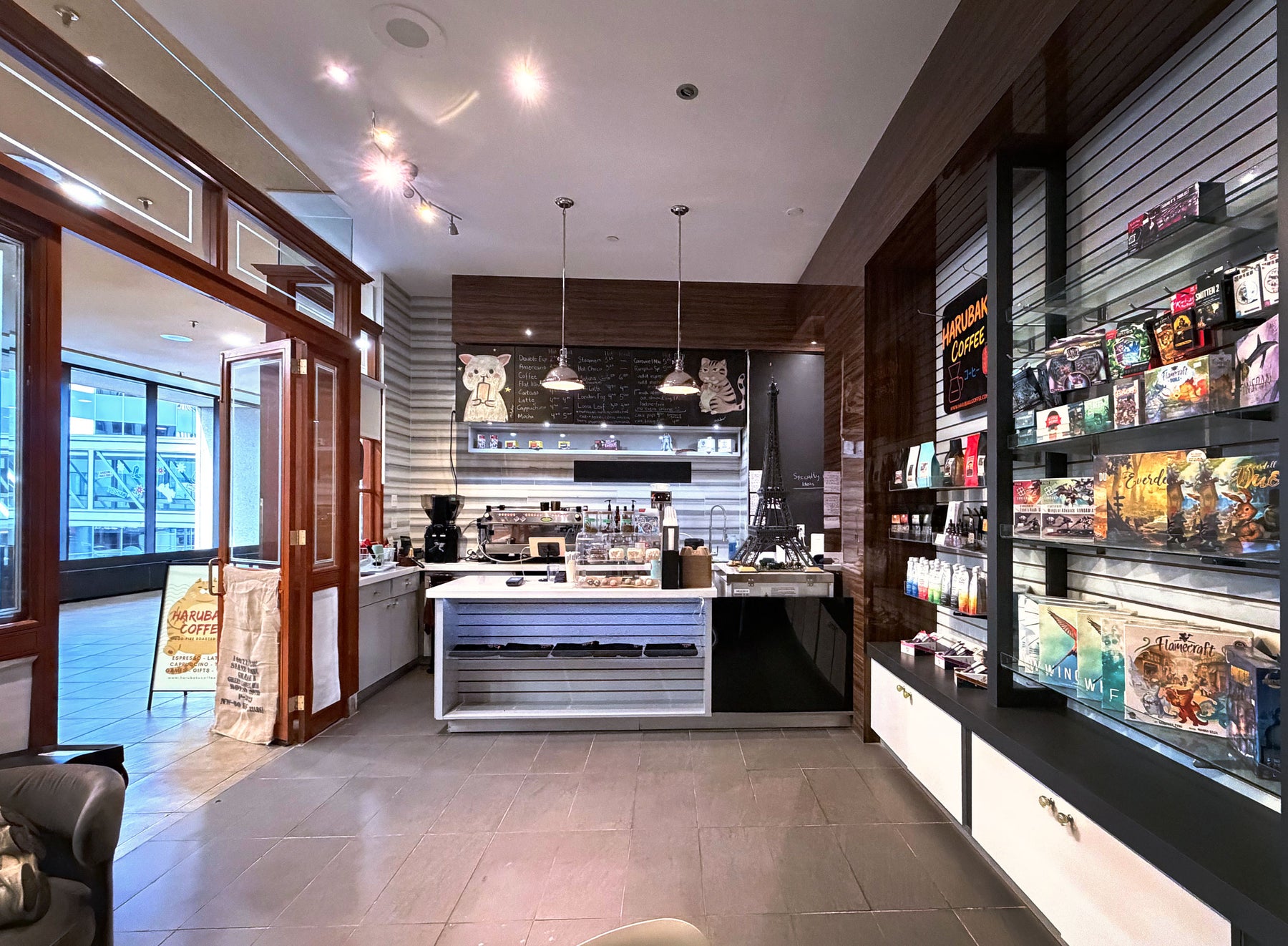Inside Harubaku Coffee Edmonton: the counter, chalkboard menu and games retail shelves